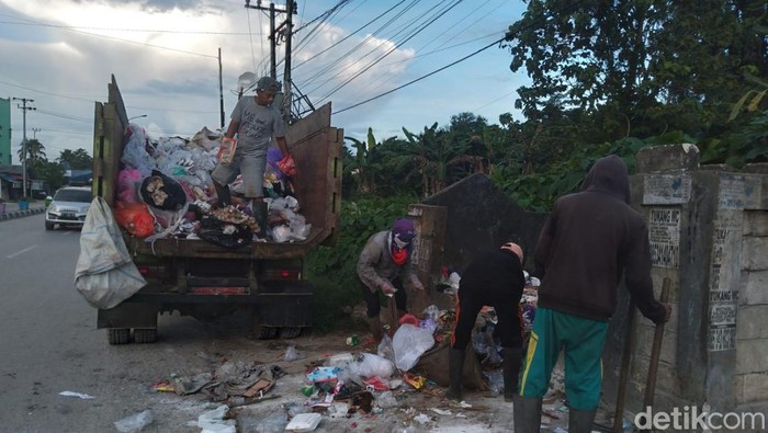 Petugas kebersihan mengangkut sampah di bak sampah pinggir jalan Kota Kendari.