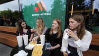Sejumlah anak muda asyik menyantap makanan cepat saji di restoran pengganti McDonalds di Rusia yang resmi dibuka Minggu (12/6/2022) waktu setempat. (Contributor/Getty Images).