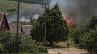 Seorang warga sipil korban perang terlihat melihat rumput yang terbakar usai penembakan yang dilakukan tentara Rusia.