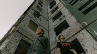 Dua orang siswa berpose di antara gedung yang rusak di kawasan Chernihiv.  