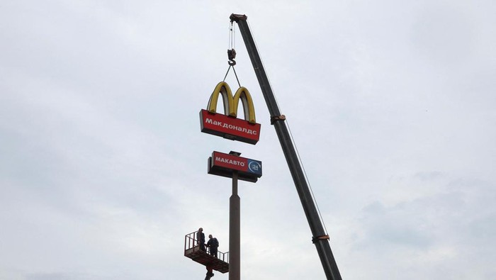 Workers use a crane to dismantle the McDonald's Golden Arches while removing the logo signage from a drive-through restaurant of McDonald's in the town of Kingisepp in the Leningrad region, Russia June 8, 2022. REUTERS/Anton Vaganov