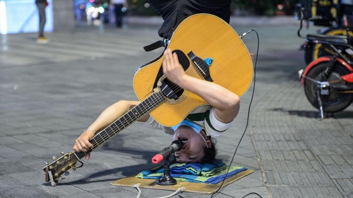 Ada-ada Saja, Pria Ini Ngamen Sambil Jungkir Balik GUANGZHOU, CHINA - JUNE 13: A man stands upside down in the street singing on June 13, 2022 in Guangzhou, Guangdong Province of China.It is understood that the man from Guangxi, China, has been singing and performing on the streets of Guangzhou for many years in order to support his two children to study. (Photo by Stringer/Anadolu Agency via Getty Images)