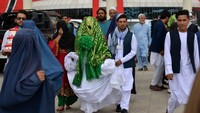 Sepasang kekasih Afghanistan berjalan di luar aula pernikahan setelah upacara pernikahan massal. Upacara dihadiri oleh ratusan tamu dan pejuang Taliban yang membawa senjata.