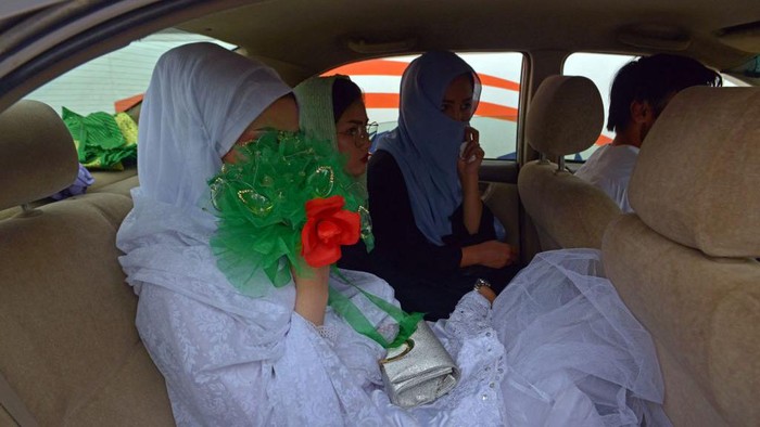 Grooms stand along with the gifts outside the wedding hall during a mass marriage ceremony in Kabul on June 13, 2022. - Dozens of Afghan women concealed in thick green shawls were married off in an austere mass wedding in Kabul, in a ceremony attended by hundreds of guests and gun-toting Taliban fighters. (Photo by Sahel ARMAN / AFP) (Photo by SAHEL ARMAN/AFP via Getty Images)