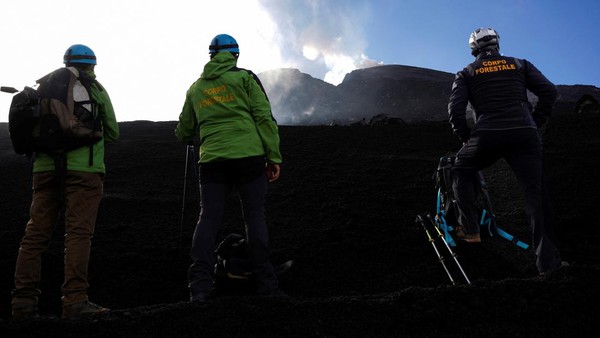 Sejumlah anggota Departemen Kehutanan Italia menyaksikan lava mengalir menuruni kawah tenggara Gunung Etna yang terlihat dari Zafferana Etnea, Italia, Sabtu (11/6/2022).
