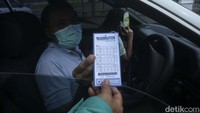 Pengendara menerima hasil uji emisi mobilnya.