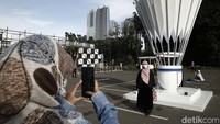 Penonton berpose di depan monumen shuttlecock raksasa.