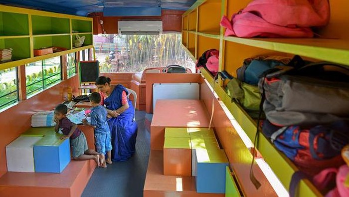 Mengubah Bus Bekas Jadi Ruang Belajar Anak-anak India Students watch an educative video playing on a television inside a re-modified low-floor old defunct public transport bus transformed into a classroom for pre-nursery school children through an initiative 'Education on Wheels' taken by the state government at Thiruvananthapuram in India's Kerala state on June 13, 2022. (Photo by Manjunath Kiran / AFP) (Photo by MANJUNATH KIRAN/AFP via Getty Images)