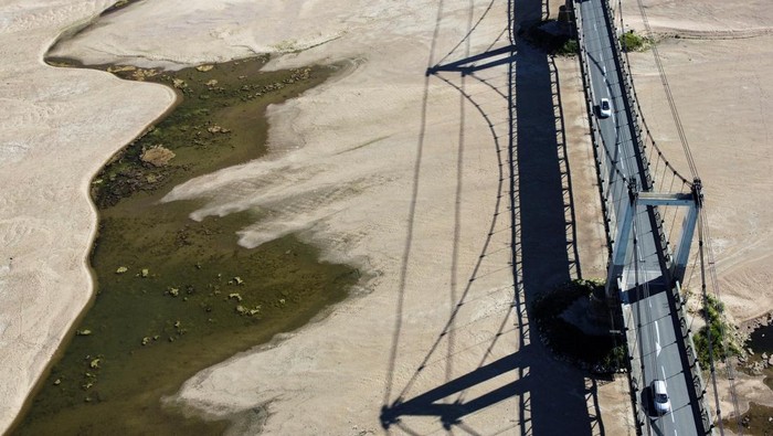 Cracked and dry earth is seen in the wide riverbed of the Loire River near the Anjou-Bretagne bridge as a heatwave hits Europe, in Ancenis-Saint-Gereon, France, June 13, 2022. REUTERS/Stephane Mahe