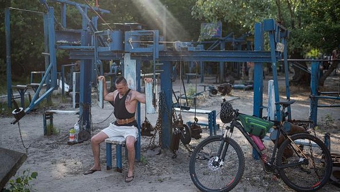 Warga Ukraina Latih Kekuatan di Gym 'Besi Tua' KYIV, UKRAINE - JUNE 13: A man works out in an outdoor gym on Hidropark on June 13, 2022 in Kyiv, Ukraine. The region around Ukraine's capital continues to recover from Russia's aborted assault on Kyiv, which turned many communities into battlefields. (Photo by Alexey Furman/Getty Images)