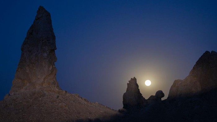TRONA, CA - JUNE 14: In an aerial view, the Strawberry Supermoon sets behind the Trona Pinnacles, which were formed underwater when this region of the Mojave Desert was under a body of water on June 14, 2022 near Trona, California. The Strawberry supermoon is not a reference to its color but to the month in which some Native Americans harvested wild strawberries.  (Photo by David McNew/Getty Images)