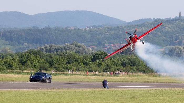 A sport airplane flies next to a Croatian electric supercar Rimac Nevera driven by Miroslav Zrncevic during a 