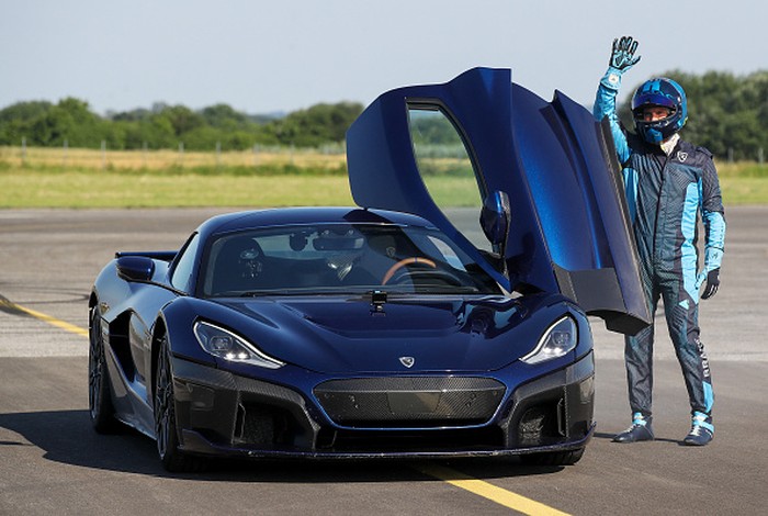 A sport airplane flies next to a Croatian electric supercar Rimac Nevera driven by Miroslav Zrncevic during a 
