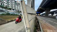 Pengendara melintas di samping tembok pembatas Tol JORR Cikunir yang tampak miring dan nyaris ambruk, Rabu (15/06/2022).