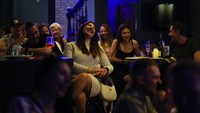 Orang-orang tertawa lepas saat menghadiri pertunjukan komedi stand-up Serhiy Lipko. 
