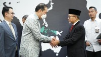 Setelah menandatangani dokumen sertijab, keduanya berjabat tangan. Terlihat Lutfi yang mengenakan batik dan Zulkifli dengan jas berdasi merah.