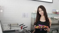 Ayu Thalia sedang memperlihatkan momen masak taco pink sendiri. Mengenakan celemek, ia siap beraksi di dapur.