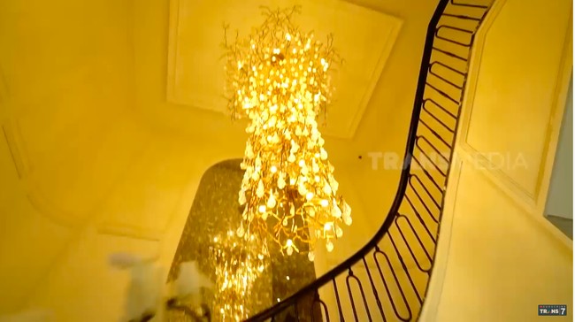 Sebuah lampu gantung bergaya modern yang menjuntai dramatis dari langit-langit di tangga utama seperti menjadi karya seni tersendiri di rumah ini. (Foto: YouTube/Trans7 Official)
