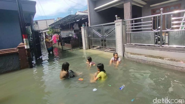 Banjir rob melanda kawasan Krembangan Surabaya. Di jalan, lalu lintas tersendat. Di permukiman, banyak anak-anak bermain air banjir.