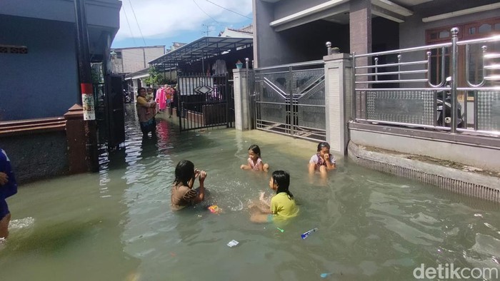 Banjir rob melanda kawasan Krembangan Surabaya. Di jalan, lalu lintas tersendat. Di permukiman, banyak anak-anak bermain air banjir.