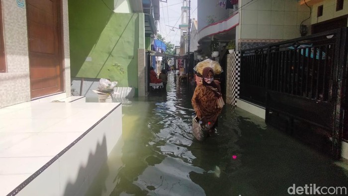 Banjir rob melanda kawasan Krembangan Surabaya. Di jalan, lalu lintas tersendat. Di permukiman, banyak anak-anak bermain air banjir.