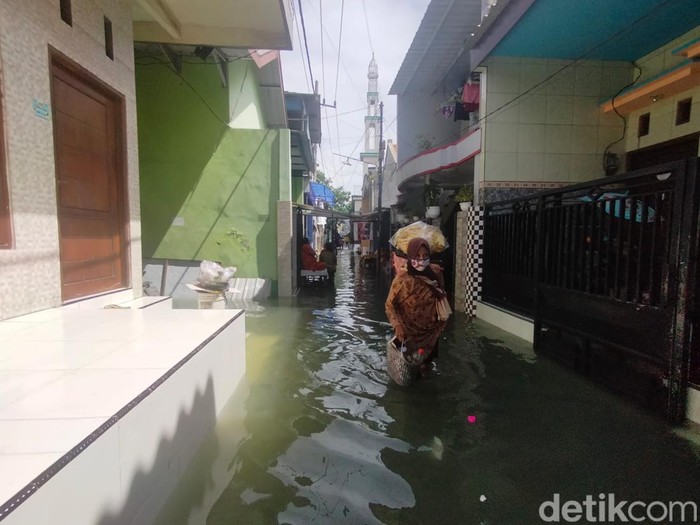 Banjir rob melanda kawasan Krembangan Surabaya. Di jalan, lalu lintas tersendat. Di permukiman, banyak anak-anak bermain air banjir.