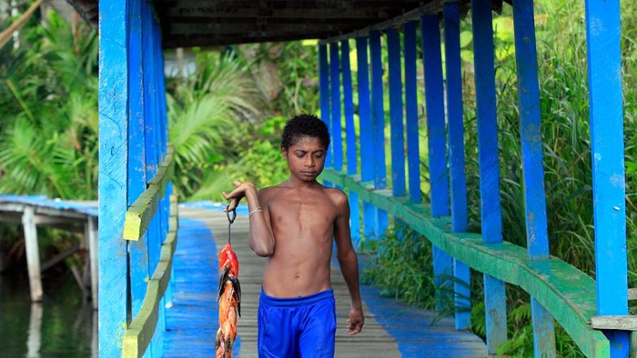 Seorang bocah membawa ikan hasil tangkapannya di Kampung Yokiwa, Distrik Sentani Timur, Kabupaten Jayapura, Papua. Rabu (15/6/2022). Pemerintah setempat berencana menjadikan kampung yang berada di tepi Danau Sentani tersebut sebagai daerah percontohan ekowisata di Papua. ANTARA FOTO/Gusti Tanati/app/rwa.
