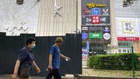 Orang-orang berjalan melewati barikade di luar area bar dan klub malam yang menjadi pusat wabah COVID-19 di Beijing. (AP/Mark Schiefelbein)