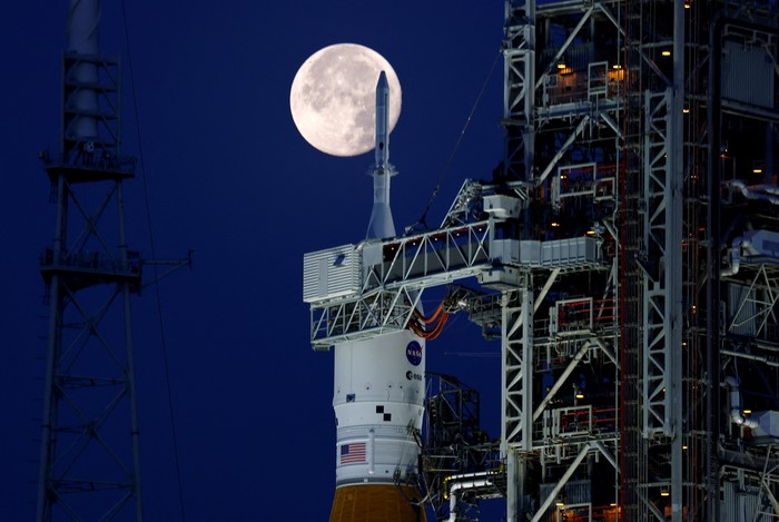 Bulan purnama stroberi terlihat di langit AS. Pemandangan tak biasa pun terlihat kala roket NASA untuk misi ke bulan terpotret bersama purnama stroberi.