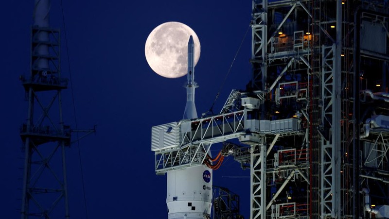Bulan purnama stroberi terlihat di langit AS. Pemandangan tak biasa pun terlihat kala roket NASA untuk misi ke bulan terpotret bersama purnama stroberi.
