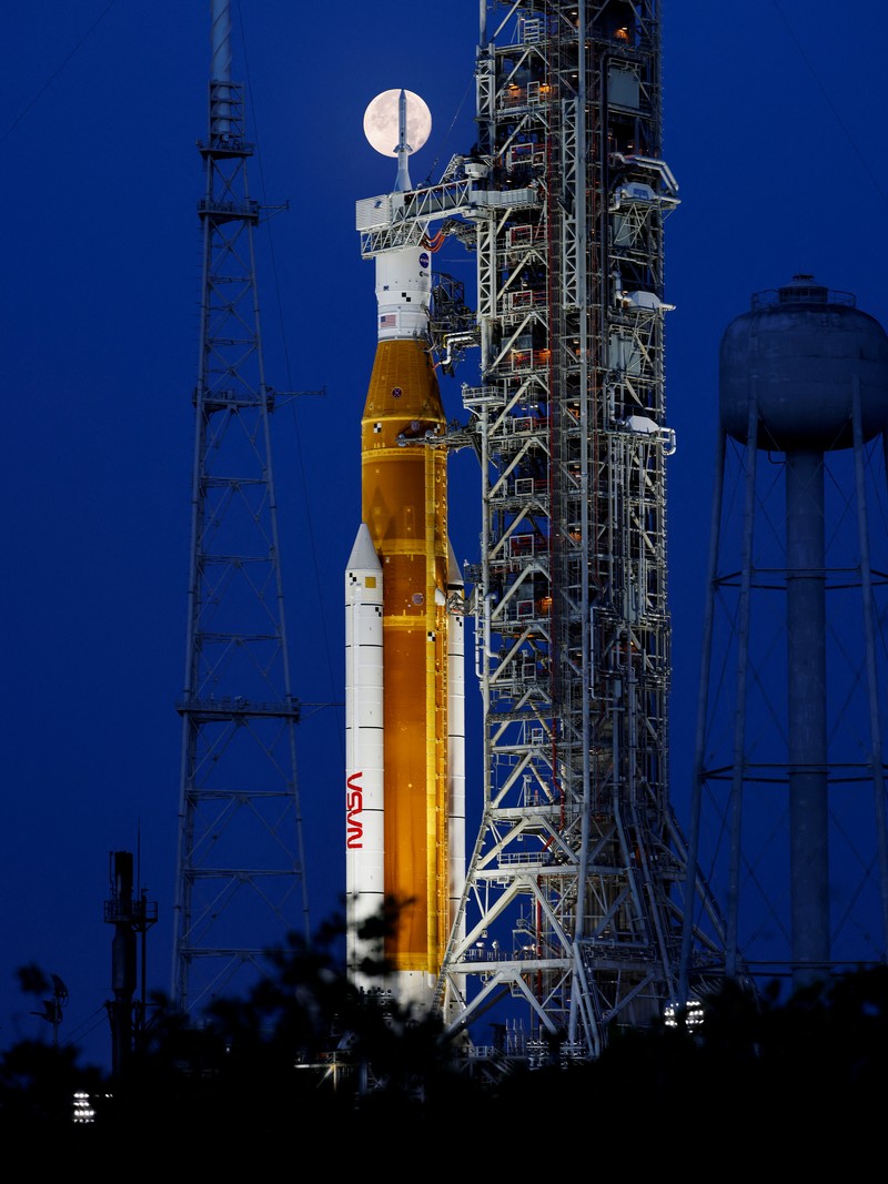 Bulan purnama stroberi terlihat di langit AS. Pemandangan tak biasa pun terlihat kala roket NASA untuk misi ke bulan terpotret bersama purnama stroberi.