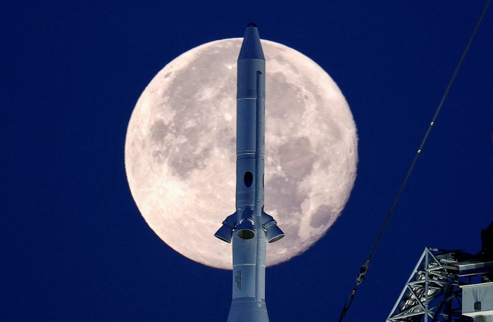 Bulan purnama stroberi terlihat di langit AS. Pemandangan tak biasa pun terlihat kala roket NASA untuk misi ke bulan terpotret bersama purnama stroberi.