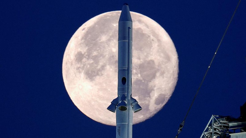 Bulan purnama stroberi terlihat di langit AS. Pemandangan tak biasa pun terlihat kala roket NASA untuk misi ke bulan terpotret bersama purnama stroberi.