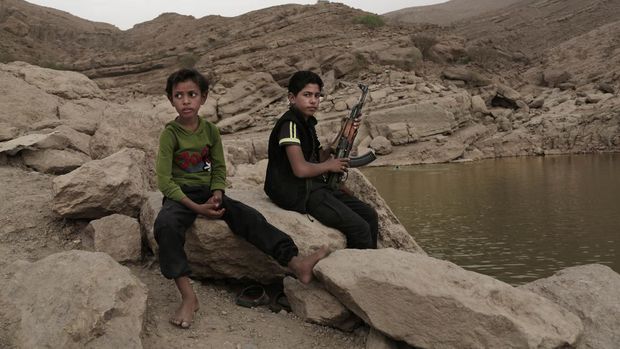 Seorang anak laki-laki berusia 17 tahun memegang senjatanya di bendungan Tinggi di Marib, Yaman, Senin (30/7/2018). Pemberontak Houthi terus berlanjut merekrut anak-anak ke dalam barisan militer mereka untuk berperang dalam perang saudara negara itu, meskipun ada kesepakatan dengan PBB pada April 2022, untuk menghentikan praktik tersebut.  (AP Photo/Nariman El-Mofty,