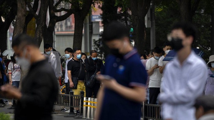 People wearing face masks stand in line at a coronavirus testing site on the third day of mass testing for millions of residents in the Chaoyang district in Beijing, Wednesday, June 15, 2022. (AP Photo/Mark Schiefelbein)