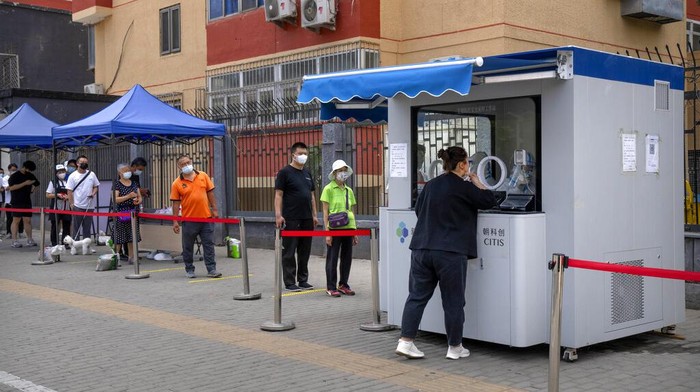 People wearing face masks stand in line at a coronavirus testing site on the third day of mass testing for millions of residents in the Chaoyang district in Beijing, Wednesday, June 15, 2022. (AP Photo/Mark Schiefelbein)