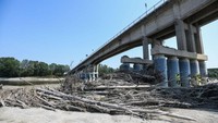 Potongan kayu tertahan di tiang jembatan yang berada di Sungai Po yang mengering.