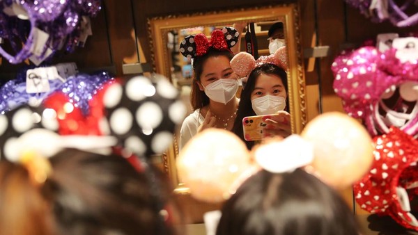 Pengunjung berfoto di World of Disney Store yang kembali beroperasi di Shanghai, China, Kamis (16/6/2022). (Zhang Hengwei/China News Service via Getty Images).