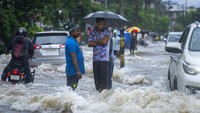 Warga berdiri di jalan yang tergenang air saat hujan deras mengguyur kota terbesar di Assam, Guwahati. Pemerintah Assam telah memerintahkan untuk penutupan semua institusi pendidikan di Guwahati karena peringatan siaga merah untuk hujan lebat.