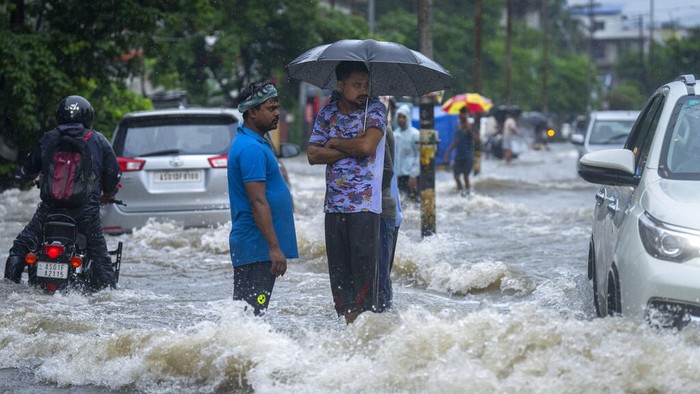 Banjir Melanda Wilayah Assam India Usai Diguyur Hujan Deras A man carries a gas cylinder on his bicycle and wades through a flooded street during heavy rainfall in Gauhati, India, Thursday, June 16, 2022. (AP Photo/Anupam Nath)