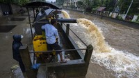 Pihak berwenang menggunakan pompa untuk mengeluarkan air dari jalan yang banjir menuju sungai.