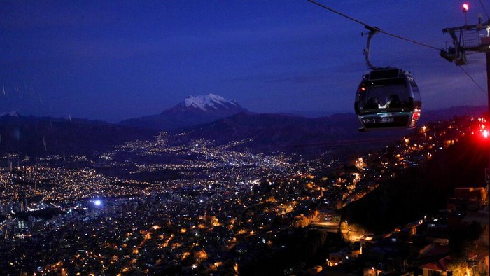 Hindari Macet, Kereta Gantung di Bolivia Jadi Angkutan Umum A cable car is silhouetted against a strawberry moon in El Alto, near La Paz, Bolivia, Thursday, June 16, 2022. (AP Photo/Juan Karita)