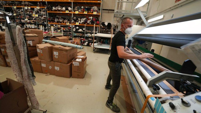 Sanksi Rusia Bikin UMKM di Italia Kebanjiran Order, Begini Kesibukannya Nadia Zanola, chairman of the Cose di Maglia and owner of the D. Exterior brand, goes through racks of clothing at a warehouse section of unsold clothes, in Brescia, Italy, Tuesday, June 14, 2022. Small Italian fashion producers are still allowed to export to Russia, despite sanctions, as long as the wholesale price is under 300 euros. But they are having a hard time getting paid, due to restrictions tied to the financial sector. (AP Photo/Luca Bruno)