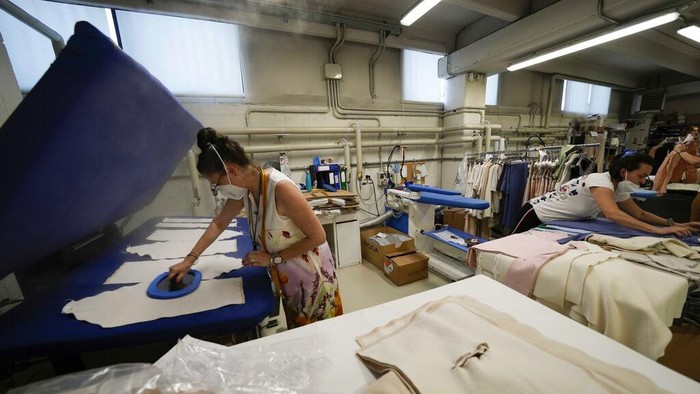 Sanksi Rusia Bikin UMKM di Italia Kebanjiran Order, Begini Kesibukannya Nadia Zanola, chairman of the Cose di Maglia and owner of the D. Exterior brand, goes through racks of clothing at a warehouse section of unsold clothes, in Brescia, Italy, Tuesday, June 14, 2022. Small Italian fashion producers are still allowed to export to Russia, despite sanctions, as long as the wholesale price is under 300 euros. But they are having a hard time getting paid, due to restrictions tied to the financial sector. (AP Photo/Luca Bruno)