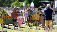Pengunjung tampak memotret karton-karton tersebut, ada yang bertuliskan Bakar Hidup-hidup Koruptor sampai Senjata Tak Selesaikan. Foto: AFP via Getty Images/INA FASSBENDER