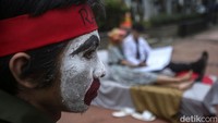 Dalam aksi teatrikal itu salah satu peserta tampak memakai ikat kepala berwarna merah.