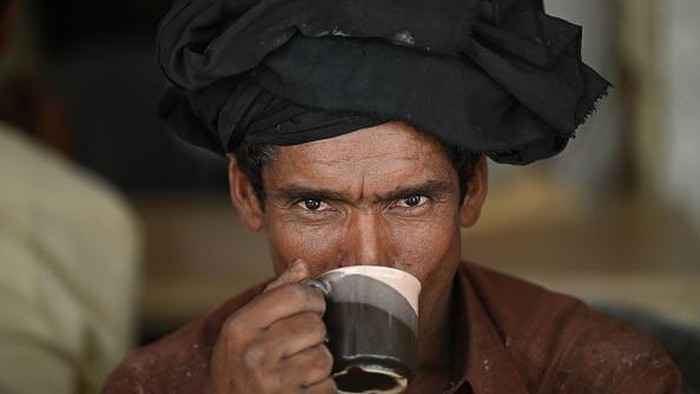 A man drinks tea from a saucer at a restaurant in Islamabad on June 15, 2022. - Pakistan is the world's biggest importer of tea -- known locally as 