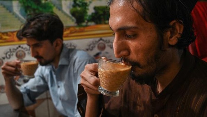 A man drinks tea from a saucer at a restaurant in Islamabad on June 15, 2022. - Pakistan is the world's biggest importer of tea -- known locally as 