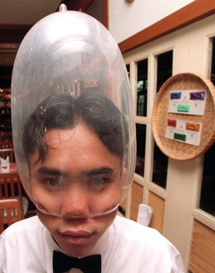 158608233 BANGKOK, THAILAND - 1994/02/01: A portrait of Mechai Viravaidya who is Thailand's leading anti AIDS activist sitting in the restaurant he founded called 'Cabbages and Condoms. Here he takes an 'after-dinner condom' instead of a mint! He has popularised condom use in Thailand and has created popular family planning clinics in the country. Such is his fame that condoms in Thailand are now known as 'Mechais'.. (Photo by Peter Charlesworth/LightRocket via Getty Images)