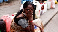 Seorang wanita mengantre untuk membeli minyak tanah sambil duduk di trotoar, di tengah krisis ekonomi di Kolombo, Sri Lanka, 17 Juni 2022.